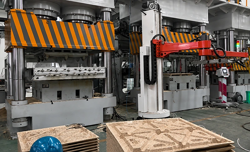 Four-column hydraulic press with gantry loading robot and high-visibility safety shielding in factory workshop