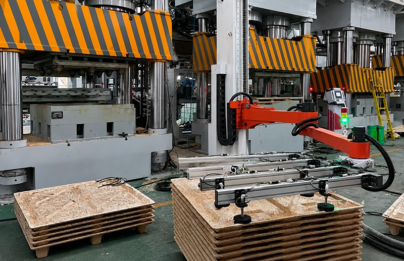 Presswood pallet take-out robot placing a freshly pressed 80 degrees pallet onto the stacking station
