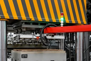 Industrial automated handling station with vacuum suction gripper, warning beacon, and striped safety enclosure