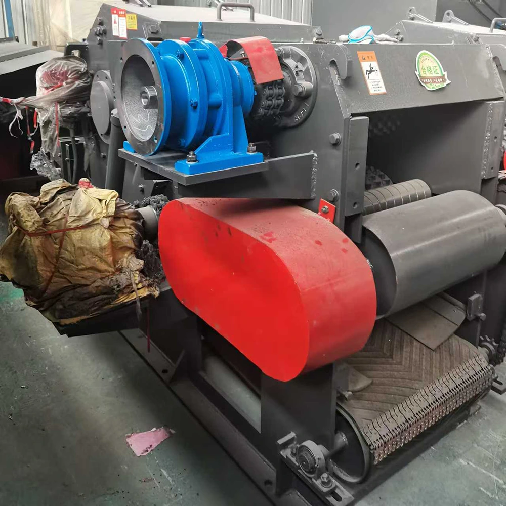 Wood log chipper machine drive side showing gear reducer, chain feed roller drive and belt guards - heavy mechanical design for irregular demolition wood infeed