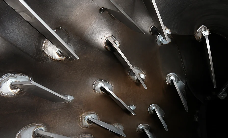 Industrial dryer chamber interior with staggered metal paddle bars, welded mounting plates, and bolted hubs
