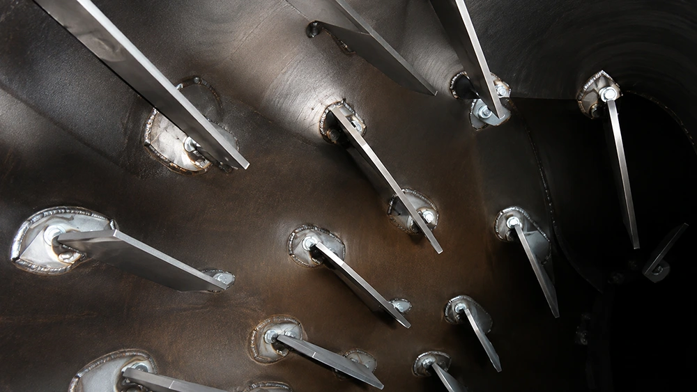Industrial dryer chamber interior with staggered metal paddle bars, welded mounting plates, and bolted hubs