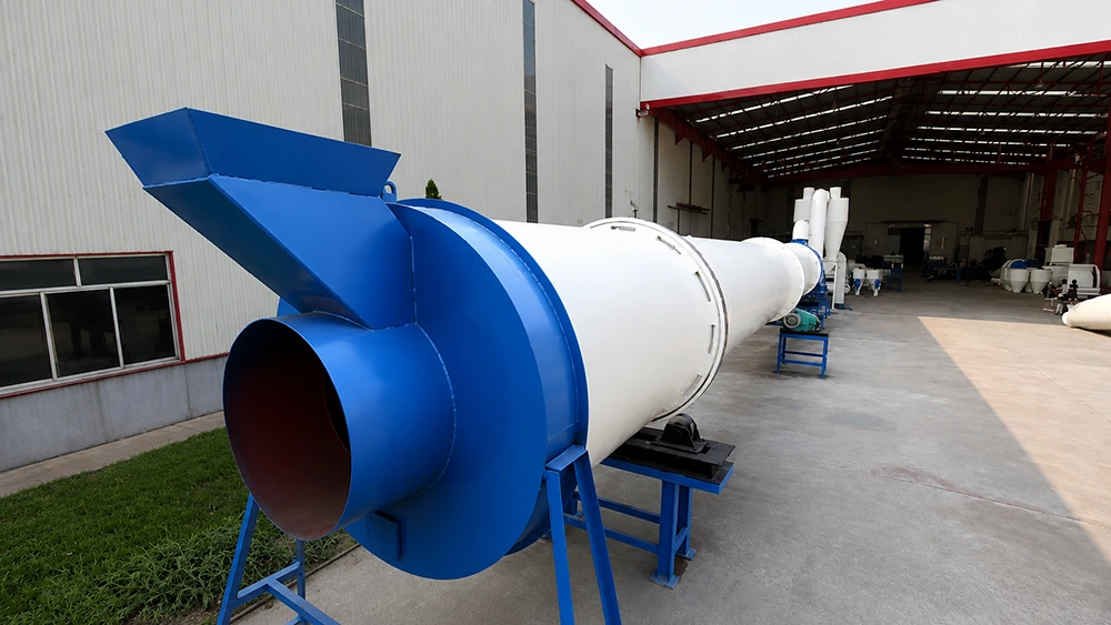 Industrial rotary drum dryer with blue feed hopper, white cylindrical shell, and roller supports