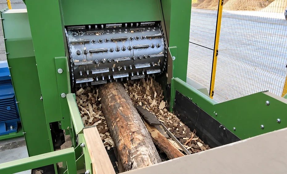 Industrial wood shredder rotor processing a bark-covered log with replaceable cutting knives for BX215 wood chipper feedstock
