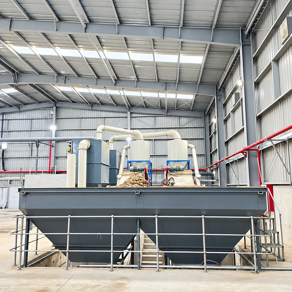 Twin steel collection hoppers beneath motor-driven equipment with ducting and safety guardrails inside factory