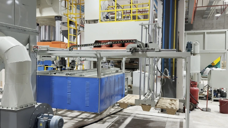 Automated servo take-out arm extracting a freshly molded wood pallet from open hydraulic press tooling.
