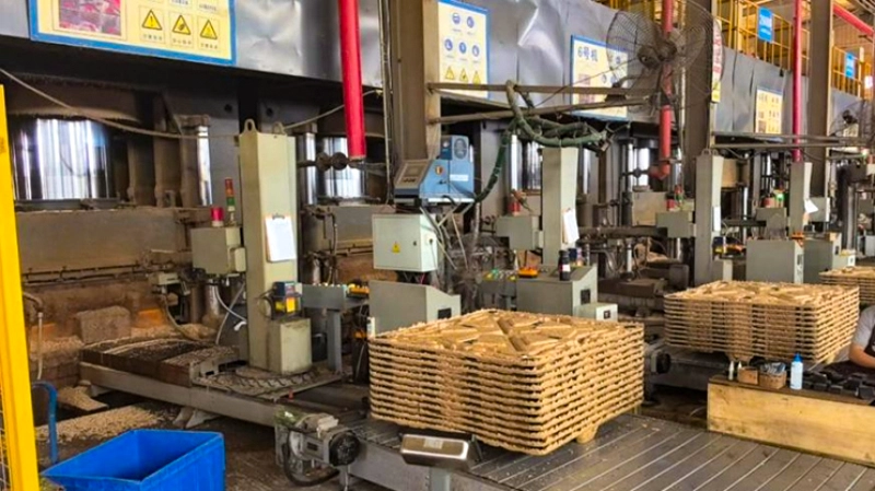 Stacks of molded wood pallets on a powered steel roller conveyor at the output end of a molded pallet production line.