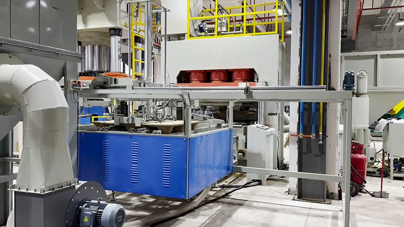 On-site photo of an automated industrial workstation with blue enclosure, gantry frame, and safety railing.
