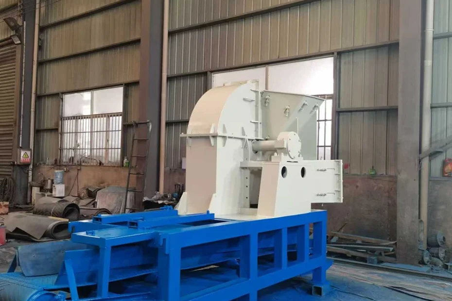 Stationary drum wood chipper machine with enclosed white housing, blue welded support frame, horizontal roller and drive sprocket