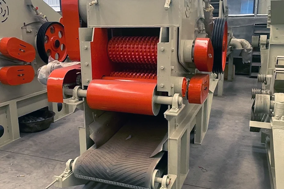 Twin-rotor industrial shredder with toothed shafts and chevron belt discharge conveyor on a drum wood chipper machine chip preparation line