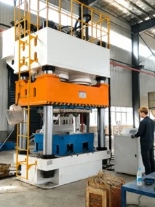Wood pallet hydraulic press with four-column frame, guide pillars, safety ladder and control cabinet in a pallet plant workshop