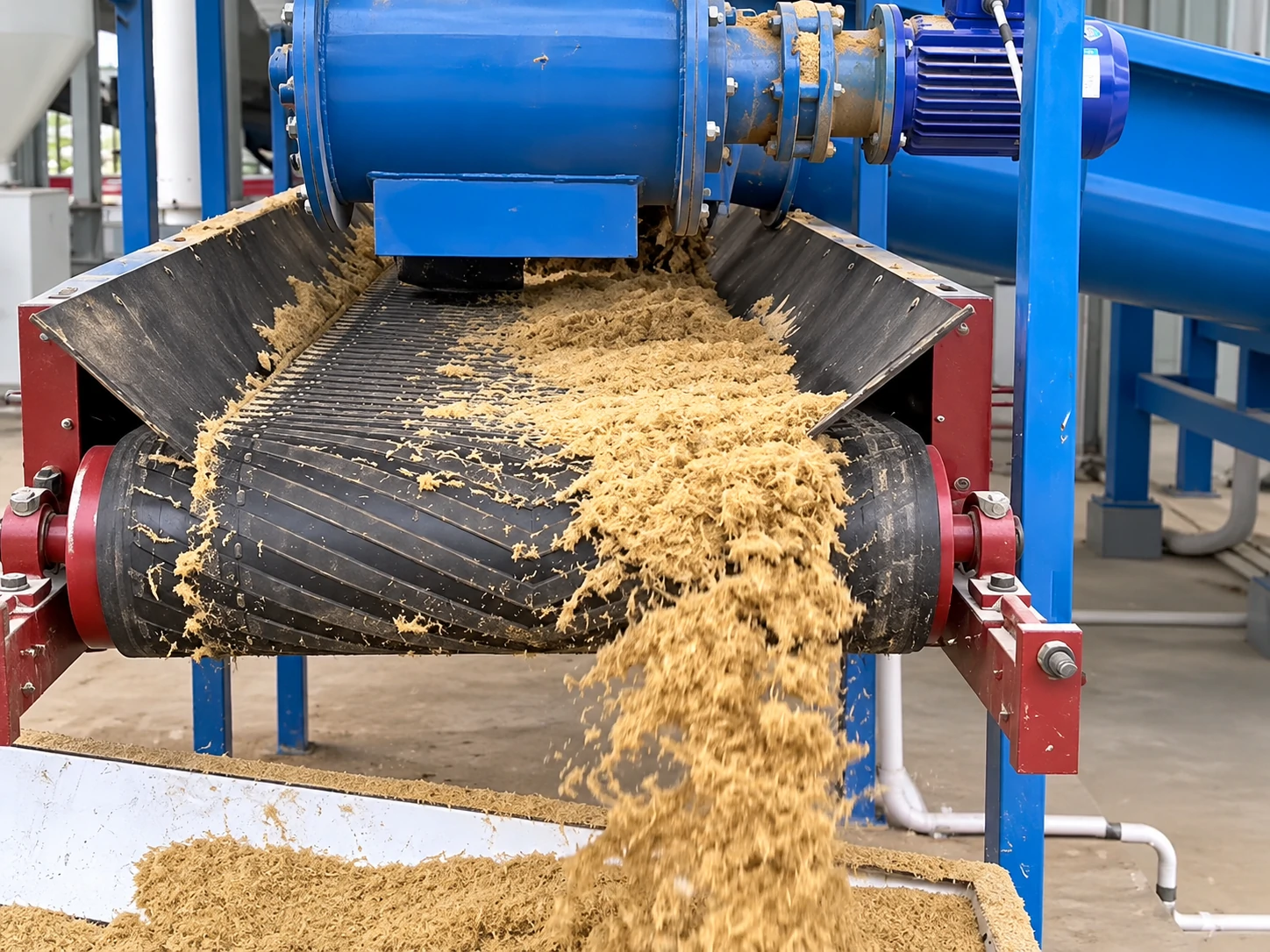 PULVZ wood pulverizer discharging fibrous biomass onto an inclined cleated conveyor for pallet board and pellet feedstock